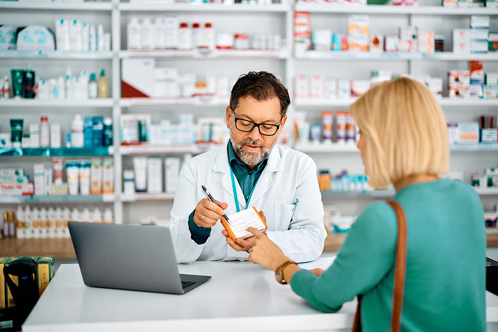 Apotheker übergibt Medikament in Apotheke